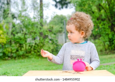 The Child Learns To Count Money. Girl With Coins In Hand. Red Wallet - Piggy Bank. Financial Literacy Of The Population.small Child Support, Alimony