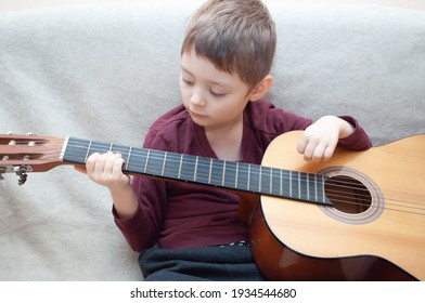 child learns to play the guitar .