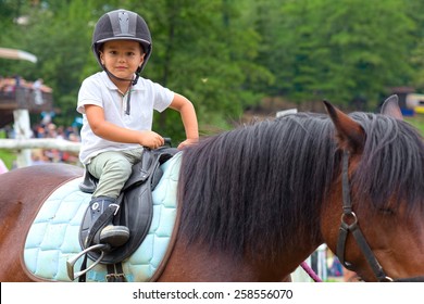 Child Learns To Ride A Horse In A Riding School Of Tuscany Alps