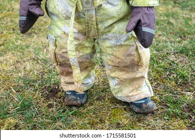 Child Legs In Yellow Muddy Winter Clothes / Jumpsuit. Baby Playing With Dirt At Rainy Weather. Gardening At Spring, Happy Childhood Concept. Exploring Outdoors With His Muddy Boots On.