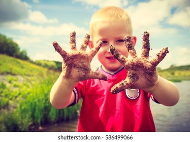 Child Little Blonde Boy Kid Playing Outdoor Showing Dirty Muddy Hands. Happy Childhood.