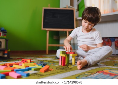 Child Little Boy Playing With Wooden Cubes Toys In Nursery At Home Or Daycare Center