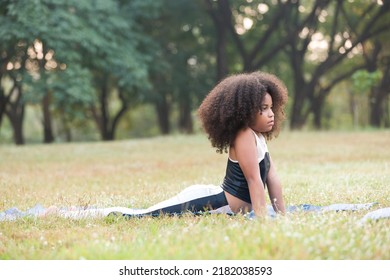 Child Little Girl Doing Meditate Yoga Asana On Roll Mat With Eyes Closed In Park. Kids Girl Practicing Doing Yoga Outdoor