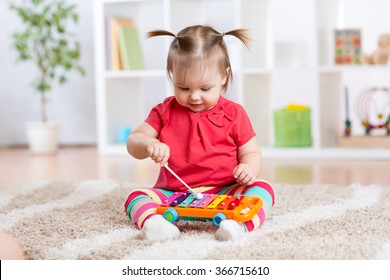Child little girl plays a musical instrument xylophone