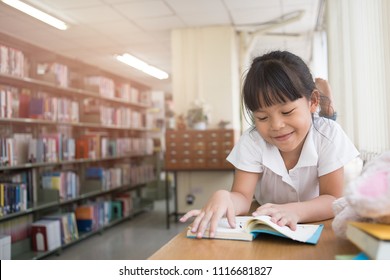 Child Little Girl Reading A Book In The Book Shop With A Rabbit Doll,Education Knowledge Concept
