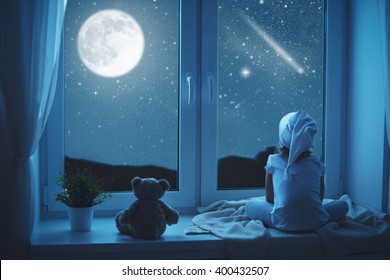 child little girl at the window dreaming the starry sky at bedtime night