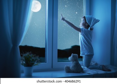 child little girl at the window dreaming  the starry sky at bedtime night