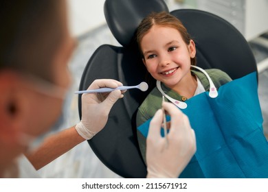 Child Little Patient Sitting On A Dental Chair Smiling On Examination At A Pediatric Dentist. Dentistry And Dental Care.