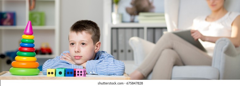 Child looking at colorful toy pyramid during a therapy session - Powered by Shutterstock