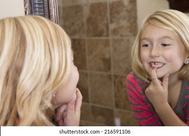 Child Looking In Mirror And Pointing At Missing Front Tooth