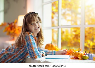 Child Looking Out Of The Window. Autumn Cozy Family Home Decoration. Kids At Home In Fall Watching Golden Leaves In Sunny Garden. Little Girl With Pumpkin On Thanksgiving Day Or Halloween.