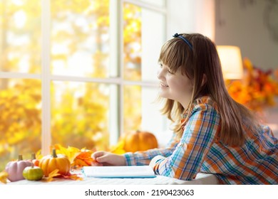 Child Looking Out Of The Window. Autumn Cozy Family Home Decoration. Kids At Home In Fall Watching Golden Leaves In Sunny Garden. Little Girl With Pumpkin On Thanksgiving Day Or Halloween.