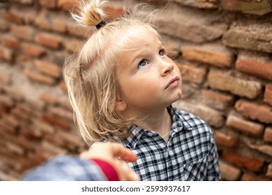 Child looking up thoughtfully with a curious expression, freckle
