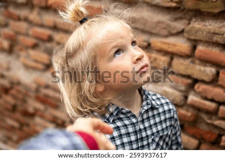 Child looking up thoughtfully with a curious expression, freckle