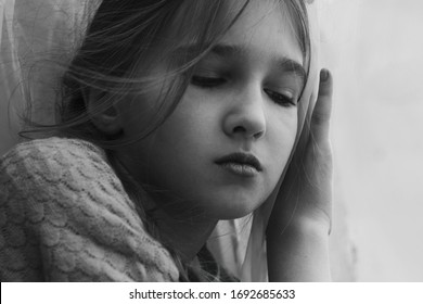 A child looks out of the window with sadness during self-isolation and quarantine. - Shutterstock ID 1692685633