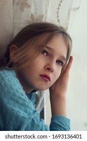 A child looks out of the window with sadness during self-isolation and quarantine. - Shutterstock ID 1693136401