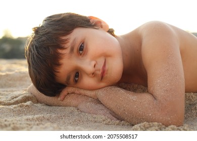 Kind, das bei Sonnenuntergang am Strand liegt