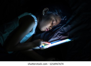 Child Lying In Bed At Night And Using Tab Let 