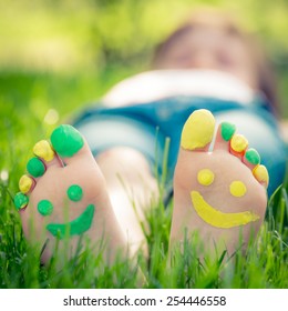 Child Lying On Green Grass. Kid Having Fun Outdoors In Spring Park