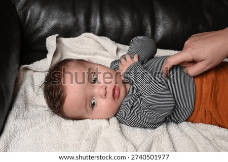 child lying on a sofa while his mother prepares him