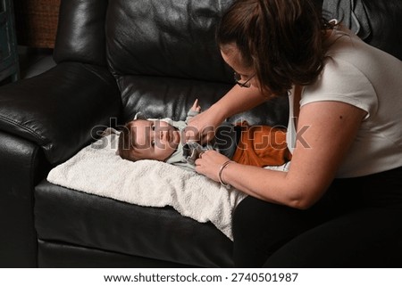 child lying on a sofa while his mother prepares him
