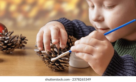 A child makes decorations for Christmas. Christmas decor made from natural materials. Christmas decorations made from pine cones. Children's creativity - Powered by Shutterstock