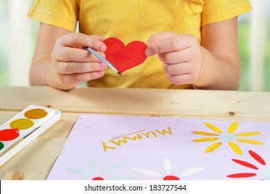 Child makes a greeting card for holiday happy mothers day