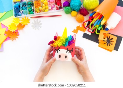 child makes a hand-made unicorn out of a tin can. Rainbow hair Favorite hobby toy. Material for creativity and tool. White background.