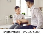 Child makes a pleasant surprise to the father. Cute little boy son gives dad a gift in a gift box in honor of his father