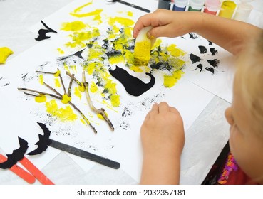 Child Making Card For The Holiday  Halloween. Funny Crafts From Paper, Natural Tree Twigs And Painting With A Sponge. The Concept For Halloween. DIY. Children's Art Project, A Craft For Children.