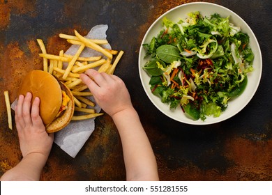 Child Making Choice Between Healthy Salad And Fast Food. Choosing Unhealthy Burger Instead Of Fresh Salad. Diet Or Healthy Lifestyle Concept