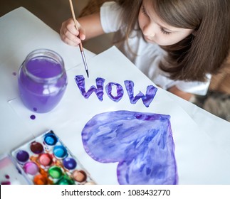Child making homemade greeting card. A little girl paints a heart on a homemade greeting card as a gift for Mother Day. Traditional play concept. Arts and crafts concept Child making homemade greeting card. A little girl paints a heart on a homemade greeting card as a gift for Mother Day. Traditional play concept. Arts and crafts concept