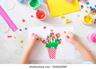 Child making homemade greeting card. little girl making vase with flowers from paper and clay, plasticine as gift for Mothers day, Birthday or Valentines day . Arts  crafts concept.