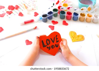 Child Making Homemade Greeting Card. A Little Girl Paints A Hearts As A Gift For Mother’s Day Or VAlentines Day. Traditional Play Concept. Arts And Crafts Concept.