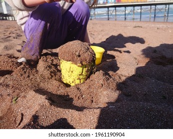 A Child Making A Mud Pie Out Of The Sand On The Beac