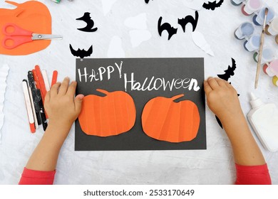 Child making paper pumpkins, black cats for the holiday of halloween. Funny crafts from paper. Halloween concept. DIY.  - Powered by Shutterstock