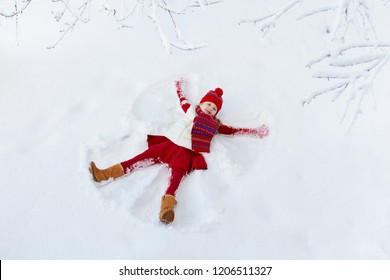 Child Making Snow Angel On Sunny Winter Morning. Kids Winter Outdoor Fun. Family Christmas Vacation. Little Girl Playing In Snow After Heavy Storm. Active Children Outdoors On Xmas Day.