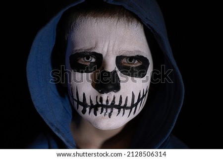 Child in mask Day of all the dead. Scary little boy smiling in halloween skull makeup.