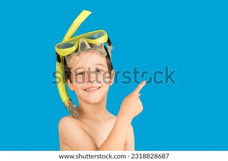 Child with mask tuba and snorkel pointing. Snorkeling, swimming, vacation concept isolated on blue background.Caucasian male model