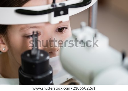 child measuring eyesight on blurred autorefractor