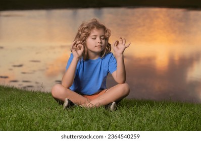 Child meditating in lotus positionon on grass, relaxing on summer nature. Happy little kid meditates on green grass at summer day. - Powered by Shutterstock