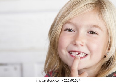 Child Missing Front Tooth Pointing At It With Her Finger