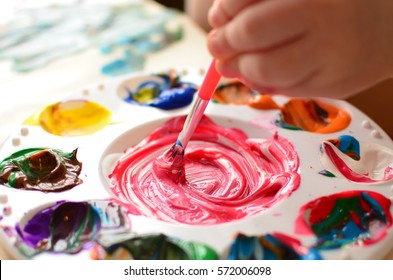 Child Mixing Paint On A Palette Of Colorful Paint