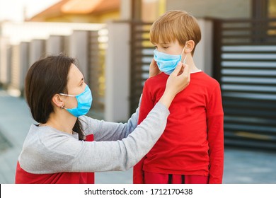 Child and mom in medical mask on a walk. Mother puts on her son sterile medical mask. Family wearing face mask for protection during the quarantine. Coronavirus outbreak and epidemic. Health care. - Powered by Shutterstock