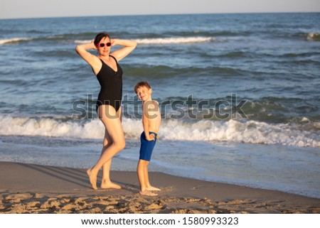 Child with mom at sea. Son teasing posing mom.