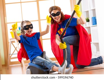 Child and mother dressed as superheroes using vacuum cleaner in room. Family middle-aged woman and kid daughter have a fun while cleaning the floor. - Powered by Shutterstock