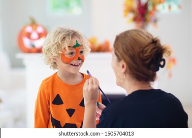 Child And Mother In Halloween Costume. Kids Trick Or Treat. Face Painting For Party Event. Little Boy Dressed As Evil Vampire With Pumpkin Lantern. Family Celebration. Mom And Son With Candy.