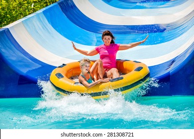 Child with mother on water slide at aquapark. Two persons on summer holiday.