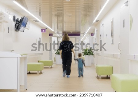 The child and mother are walking hand in hand down the long hospital corridor. Kid aged two years (two-year-old boy)