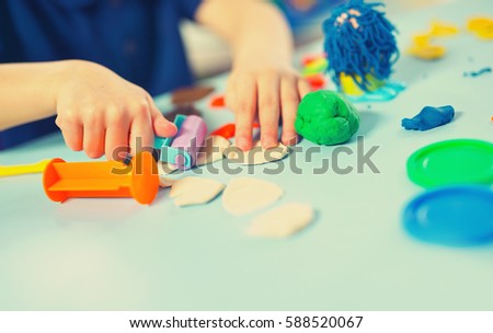Child moulds from plasticine on table. Hands with plasticine.